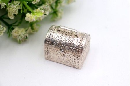 Caixa de comprimidos em forma de mala com gravados e pega na tampa basculante